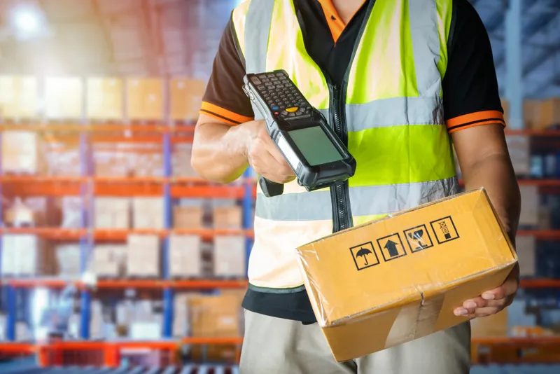 Man in warehouse scanning a box with a mobile device